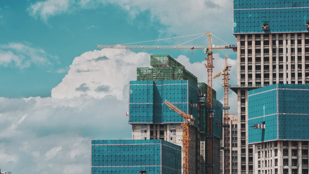a-group-of-tall-buildings-under-a-cloudy-blue-sky-91aqt9p4mo8